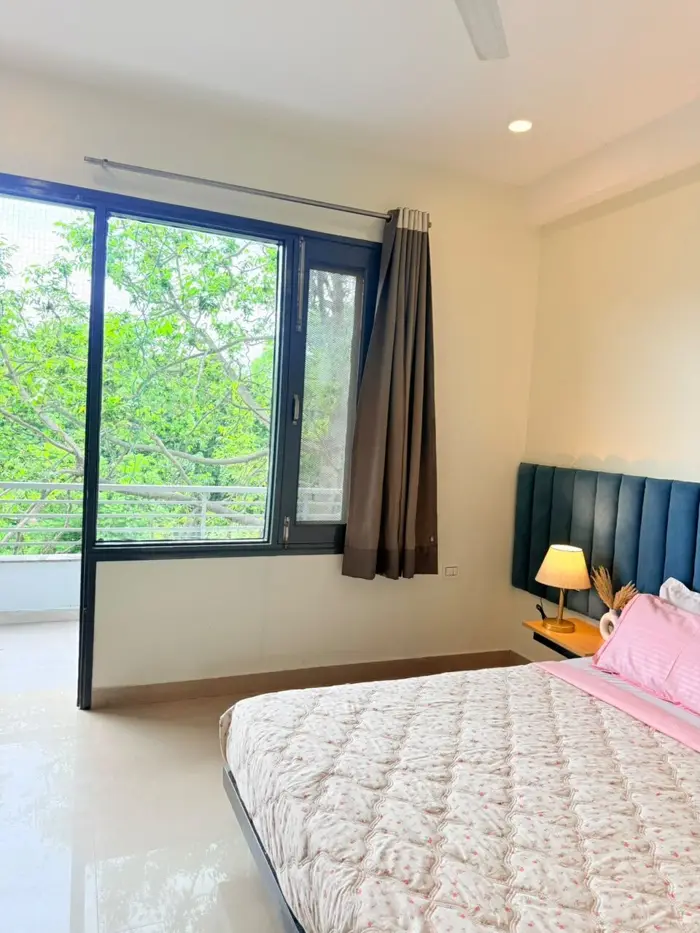 Bedroom with upholstered headboard and large window overlooking greenery